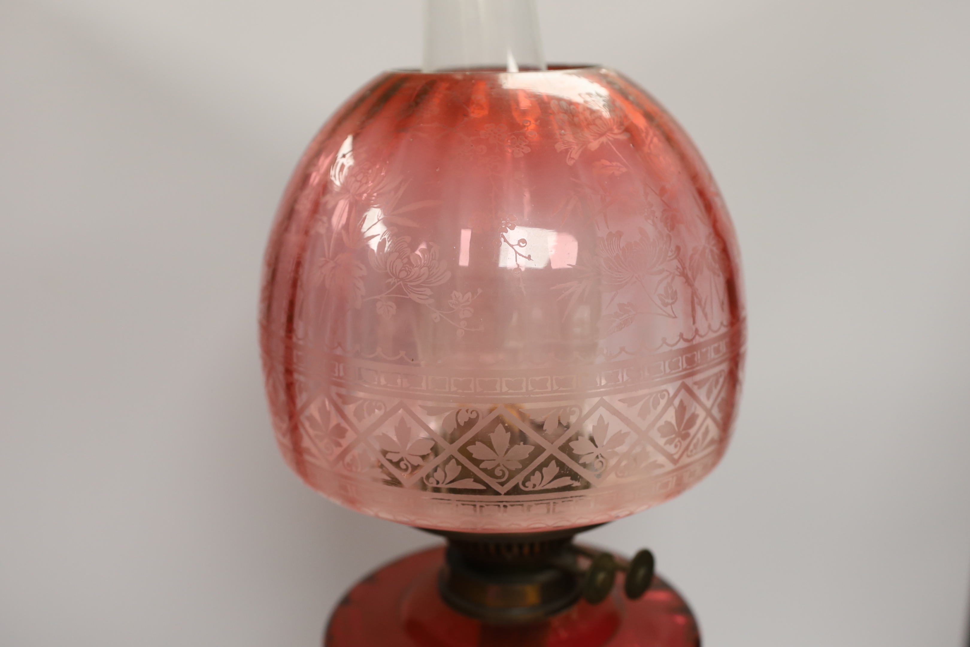 19th century brass oil lamp with cranberry glass reservoir, etched shade and Ruskin type cabochon panels to the base, 68cm high overall